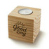 A wooden cube candle with a metal holder on top and a "Good Day" design etched into the surface.