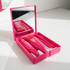 A pink plastic mirror box containing five brushes, including two larger brushes and three smaller ones.