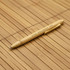 A bamboo pen with a clip, resting on a bamboo mat. It features a light wood colour and has branding on its side.