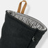 A black oven mitt with a striped interior and a hanging loop, featuring a small logo.