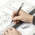 A pencil set in a hand drawing over architectural plans, with a ruler beside the pencil on a clear surface.