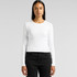 A woman wearing a white long-sleeve tee paired with black jeans, featuring a logo on the side.
