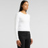 A long-sleeve white t-shirt is displayed on a model, paired with black jeans. The shirt has a simple design and a logo.