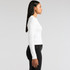 A white long-sleeve t-shirt is displayed on a model, shown from the side, paired with black jeans. It has a logo.