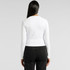 A white long-sleeve tee with a fitted design, featuring a logo on the back, worn with black pants.