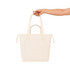 A hand holds a cream-coloured tote bag with two handles and a front pocket. The bag features a logo.