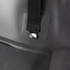 A close-up of a black bucket bag featuring a strap and a small logo. The texture appears durable and water-resistant.
