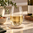 A drink bottle with a transparent, curved design, filled with a golden liquid, resting on a coaster.