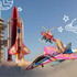 A wooden model rocket ship in red and silver, set against a blue sky with illustrated planets and flying vehicles.
