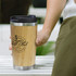 A drink bottle with a bamboo exterior and stainless steel rim, featuring a logo on the front.