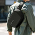 A black sling bag is worn over the shoulder, featuring a sleek, minimalist design and a logo.