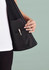 A black women's vest with a zip front, featuring an interior pocket and a hand holding the pocket.