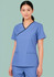 A woman in a blue scrub top with a contrast crossover design, featuring two front pockets and a logo.