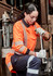 An orange long sleeve polo shirt with reflective stripes, worn by a person working on machinery.