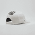 A white six-panel snapback cap with a brand logo and a tag attached.