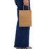 A medium brown paper bag is being held by a person, featuring a paper handle. The person is wearing blue jeans.