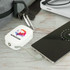 A white power bank with a logo, connected to a smartphone, placed on a grey surface beside a bag.