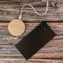 A round bamboo wireless charger in natural wood finish next to a sleek black smartphone on a wooden surface.