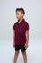A maroon polo shirt for kids, made of soft fabric, featuring a collar and short sleeves. It has a logo on it.