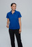 A woman in a blue polo shirt stands smiling against a neutral background, wearing black trousers. The shirt features a logo.