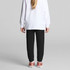 Black track pants for kids, featuring a tapered fit and cuffed ankles, paired with a white long-sleeve top.