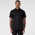 A black button-up shirt with short sleeves, featuring a logo and white buttons, modelled by a man.