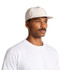 A cap in light beige worn by a man with a moustache, featuring a solid design and a logo.