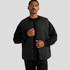 A quilted vest in black, featuring a snap button closure and a plain design, worn over a black long-sleeve shirt.