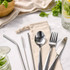 A stainless steel cutlery and straw set in a calico pouch, featuring a spoon, fork, knife, and straws.