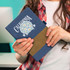 A denim notebook with a brown leatherette band, held by a person. The notebook features a decorative design and a logo.