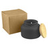 A black candle in a round jar with a bamboo lid, accompanied by a brown cardboard box.