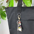 A black nylon tote bag featuring a keyring with various charms attached.