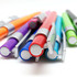 A collection of plastic pens in various colours, including purple, orange, red, blue, green, and turquoise, with silver accents.
