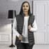 A woman wearing a black TRENDSWEAR Frazer women's puffer vest over a white top, standing indoors.