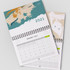 A wall calendar featuring a spiral binding, with abstract designs in teal, orange, and beige for January 2021.