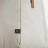 A beige backpack with a leather strap and a small logo tag on the side.