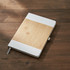 A notebook with a bamboo cover and white accents, resting on a wooden surface.
