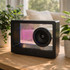 A sleek black speaker with a transparent design, featuring a central speaker and illuminated elements.
