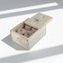 A wooden box containing multiple classical wood wine stoppers. The box has a logo and a light natural finish.