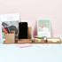 A desk organiser set in brown, featuring compartments for sticky notes, a phone, and pens against a pastel background.