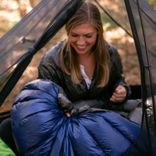 an in use photo of a person utilizing their navy blue lightweight quilt inside of their bivy