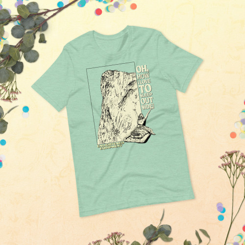 Laid out teal T-Shirt with design of a mountain and a person in a sleeping bag by the mountains.
