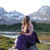 photo of a woman sitting in the enigma with a view of mountains in the back, the enigma in the picture is purple