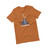 Laid out orange T-Shirt with design of a dog in a sleeping bag in the mountains.