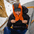 in use shot of a orange and charcoal grey adjustable lightweight, synthetic insulated, warm hood in the mountains after a goodnights sleep in a tent