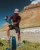 Hiker using the Sawyer Squeeze Water Filter System outdoors near a river in a desert canyon