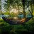 StarLite Hammock Elite 11ft Gray suspended between trees at lakeside campsite during sunset