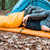 in use shot of a person showing how to use quilt layering adapters by connecting 2 quilts with the original straps in a campsite