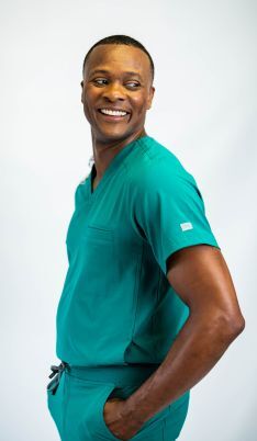 Man standing with arms crossed in scrubs