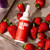 A bottle of Colour Mill Chocolate Drip red surrounded by Strawberries
